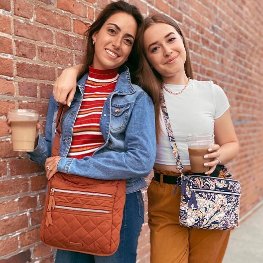 Two models holding coffee and wearing Vera Bradley crossbody bags 